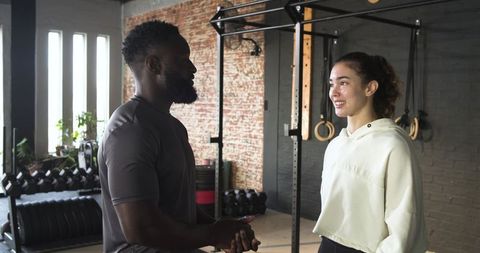 Trainer Engaging with Female Client in Gym Environment