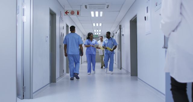 African american male and female doctor in discussion walking in busy hospital corridor - Download Free Stock Photos Pikwizard.com
