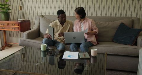Diverse Team Collaborating on Sofa with Laptop and Documents