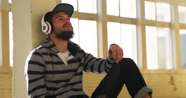 Young Man Relaxing with Headphones in Sunlit Room - Download Free Stock Images Pikwizard.com