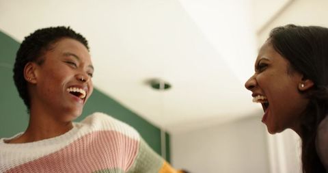 Two Female Friends Laughing Indoors in Cozy Setting
