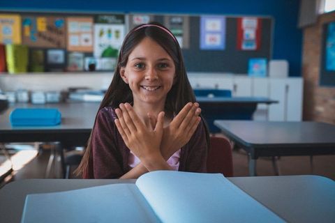 Smiling schoolgirl with hand gesture enthusiastic about learning
