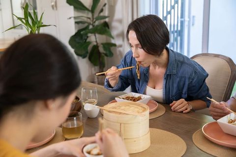 Friends Eating Traditional Asian Meal with Chopsticks at Home