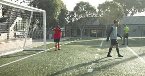 Youth soccer player aiming for goal on sunny field