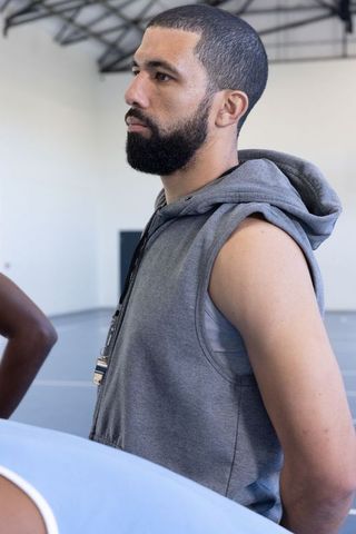 Basketball Coach Motivating Players in Gymnasium