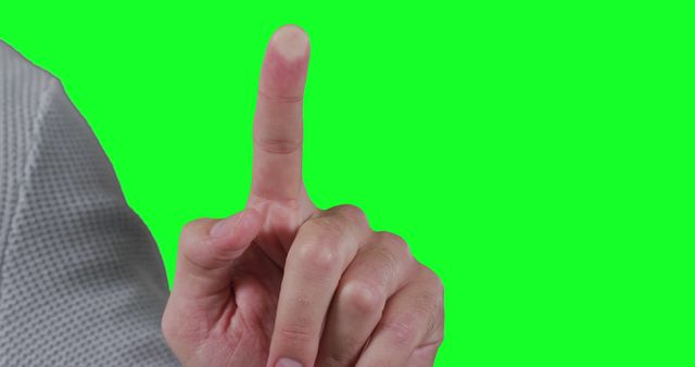 A Caucasian hand is gesturing with one finger raised against a green screen background, with copy space. This gesture could indicate a point being made or a need for attention in a presentation or instructional setting.