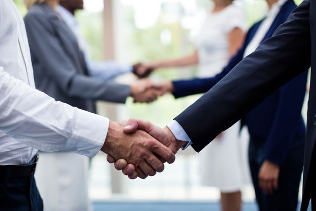 Business executives shaking hands, signifying successful agreement and partnership. Ideal for use in business presentations, articles on corporate partnerships, and materials promoting professional networking events.