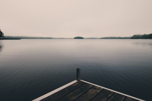 Serene Lake with Wooden Dock Under Overcast Sky - Download Free Stock Photos Pikwizard.com