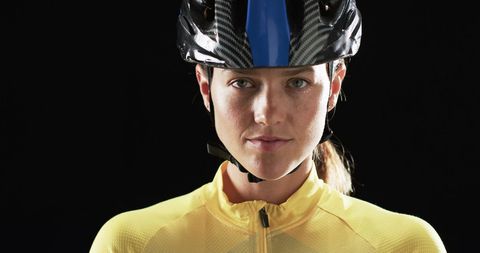 Confident female cyclist in yellow jersey with helmet