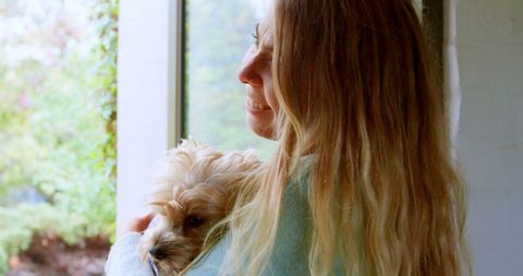 Joyful Teen Girl Embracing Small Dog by Window