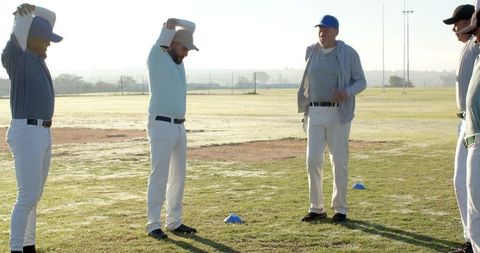 Baseball Team Stretching and Coach Instructing Morning Warmup on Grass Field