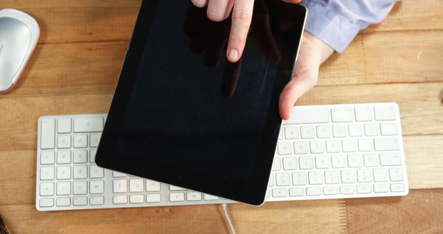 Hand Holding Tablet Above Desk with Keyboard and Mouse - Download Free Stock Images Pikwizard.com