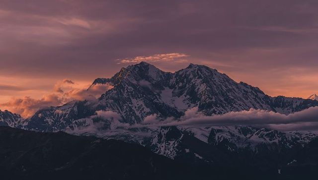Majestic snowy mountain peaks at sunset with dramatic clouds