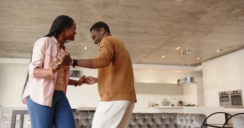 Couple Joyfully Dancing Together at Home in Modern Living Space