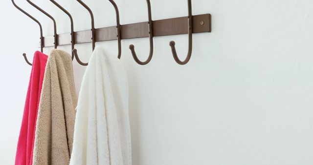 Pink, beige and white towels hanging on brown hanger rack, copy space. Towel, hanging and hanger rack concept, unaltered.