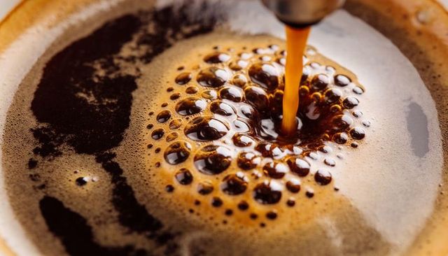 Pouring espresso creating glossy crema vortex macro close-up coffee bubbles foam