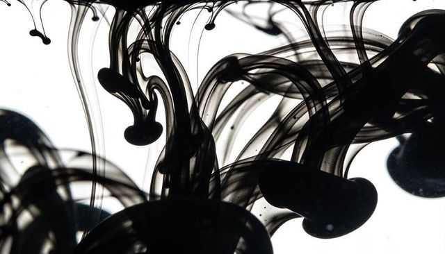 Flowing black ink tendrils curling through clear liquid backlit high-key abstract