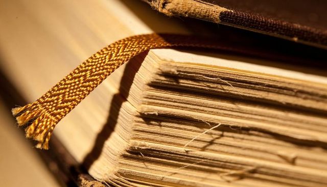 Vintage hardcover book macro showing deckled pages, spine stitching and braided bookmark