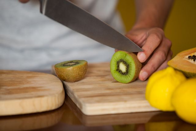 Mid-section of male staff cutting kiwifruit at organic section in supermarket