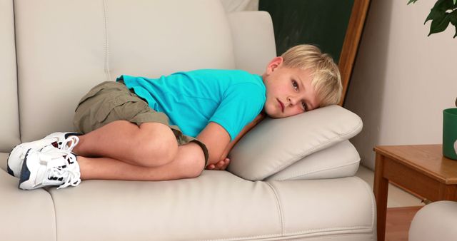 Sad little boy lying on the couch at home in the living room