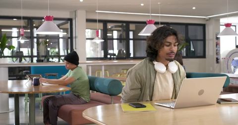 Young African American Man Working on Laptop in Modern Coworking Space with Headphones