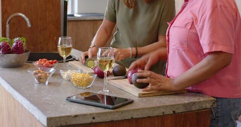 Friends cooking together: chopping vegetables at modern kitchen island