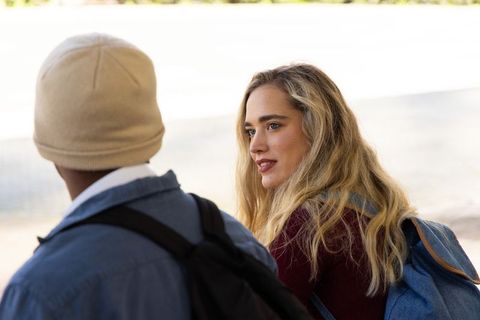 Teen friends chatting on college campus bench with denim backpack and beanie