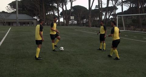 Soccer players in yellow jerseys practicing teamwork techniques