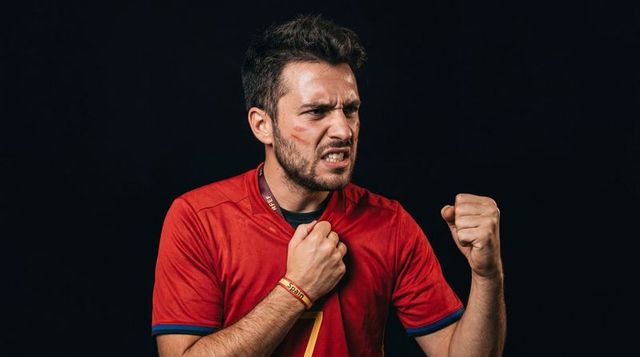 Passionate soccer fan clenching fist wearing spain red jersey showing determination
