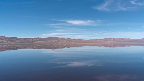 Reflecting tranquil high desert lake mirroring ridge and wispy cirrus sky minimal symmetry