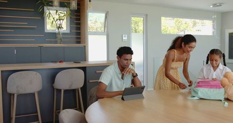Family preparing daughter for school in modern kitchen