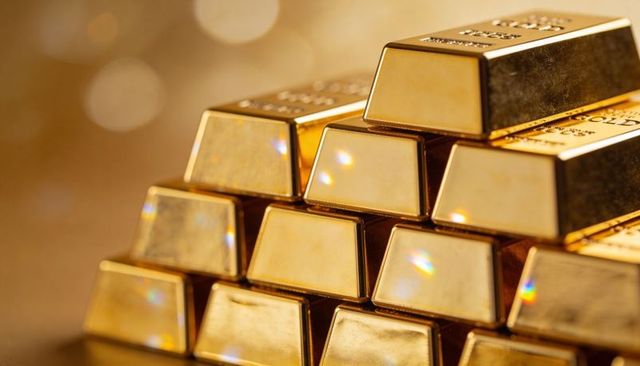 Stacked gold bars reflecting warm studio light in vault with stamped markings and bokeh