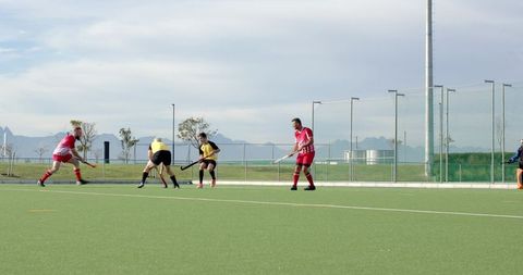 Men playing field hockey match on turf during chilly day