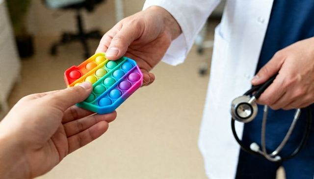 Clinician receiving rainbow pop-it fidget from patient in clinic