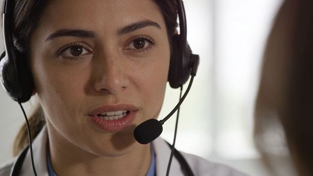 Female clinician speaking on telemedicine call wearing headset and stethoscope