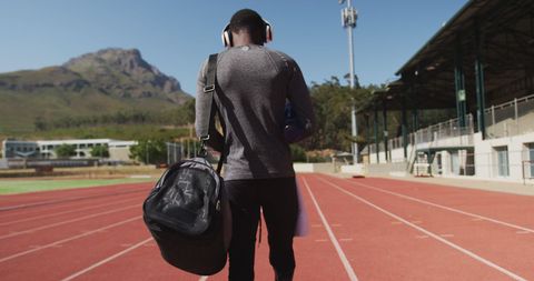 Dedicated Athlete Walking on Track with Headphones