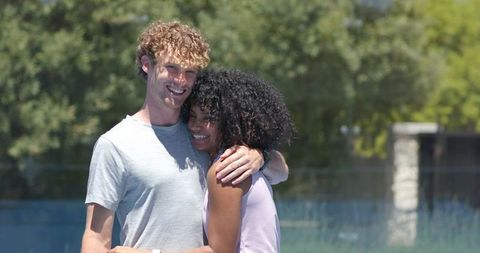 Young couple hugging and smiling by backyard pool on sunny summer day, outdoor romance