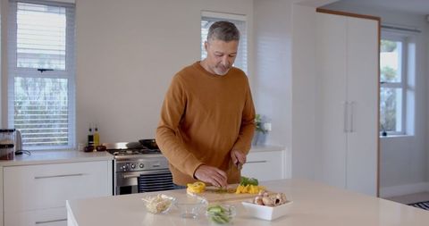 Senior Man Cooking Fresh Vegetables in Modern Kitchen