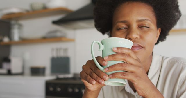 Happy african american woman drinking coffee in kitchen. domestic lifestyle, spending free time at home.