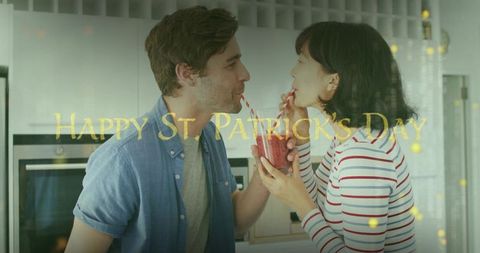 Couple sharing berry smoothie in cozy kitchen with gold happy st patrick's day overlay
