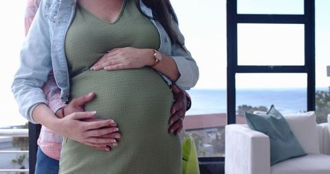 Pregnant partners embracing in ocean view home