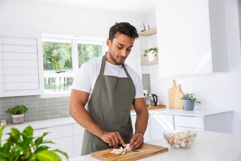 Asian Chef Skillfully Slices Fresh Mushrooms in Modern Kitchen