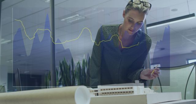 Businesswoman Analyzing Charts and Architectural Model in Office - Download Free Stock Images Pikwizard.com