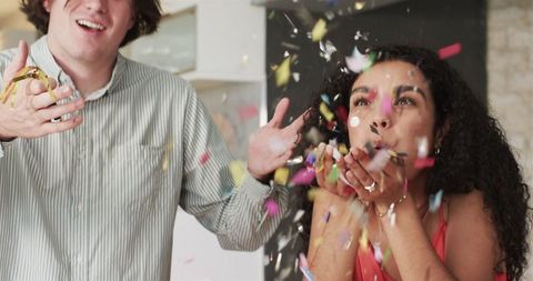 Multiracial couple celebrating with confetti at anniversary party