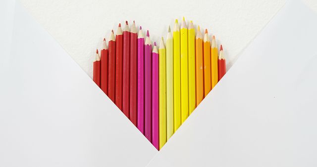 Colored pencils are arranged in a heart shape on a white background, with copy space. This creative display symbolizes love for art and the joy of coloring.