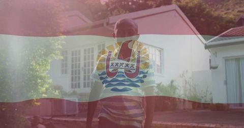 Boy standing outside home with french polynesian flag overlay