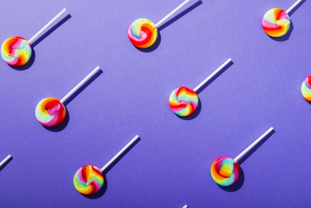 Directly above view of fresh multi colored swirl pattern lollipops arranged on blue background. unaltered, unhealthy eating and sweet food concept.