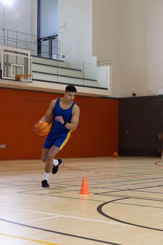 Athletic Man Dribbling Basketball on Indoor Court