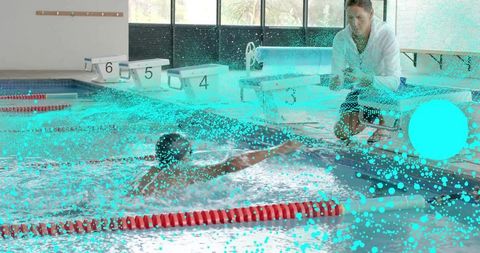 Competitive swimmer reaching for ball during coach-led training session at indoor lap pool