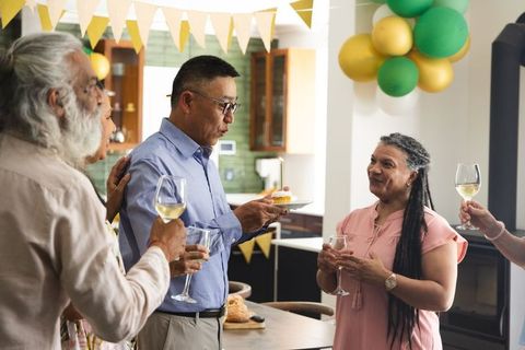 Man giving birthday speech holding cupcake while friends raising wine glasses